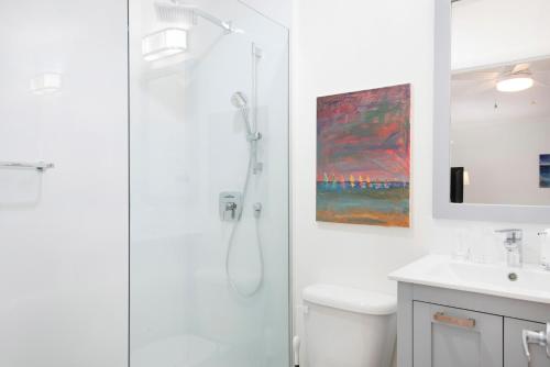 baño blanco con ducha y lavamanos en Snug Harbour View Condo #8 en George Town