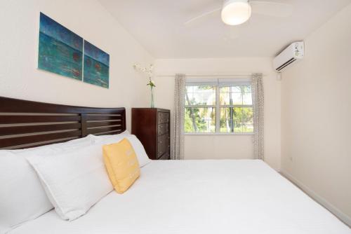 a bedroom with a large white bed with a yellow pillow at Snug Harbour View Condo #8 in George Town