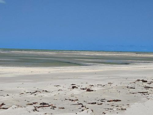 a beach with sand and the ocean in the background at Aconchegante casa perto da praia da Enseada dos Golfinhos OBS não é Jaguaribe in Jaguaribe