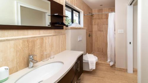 W łazience znajduje się umywalka, toaleta i lustro. w obiekcie Seven Mile View Condo #1 w mieście West Bay