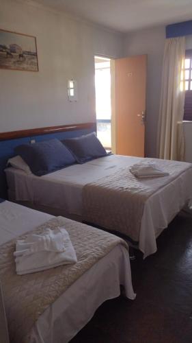 a hotel room with two beds and a window at Pousada A Pérola in Rio de Contas
