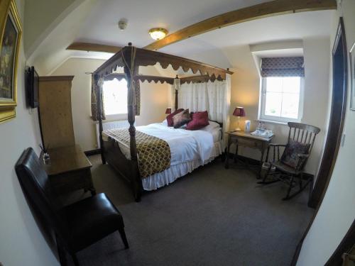 a bedroom with a canopy bed and a table with a chair at The Crown Inn in Horsted Keynes