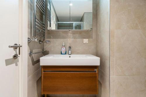 La salle de bains est pourvue d'un lavabo blanc et d'un miroir. dans l'établissement Wonderful apartment 2 bedroom with pool, à Istanbul