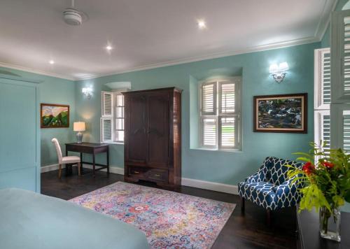 a bedroom with blue walls and a desk and a bed at Melrose Apartment in Roseau