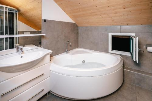 a bathroom with a tub and a sink and a tv at Chalet Prinz in Murau