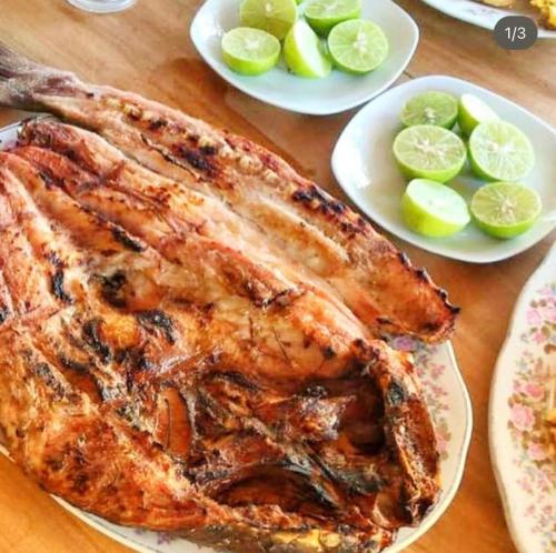 a table with two plates of meat and plates of limes at El Remanso del Santuario in Camarones