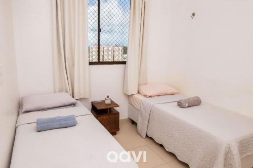 two beds in a room with a window at Qavi - Apartamento aconchegante no melhor de Ponta Negra #1603Áurea in Natal