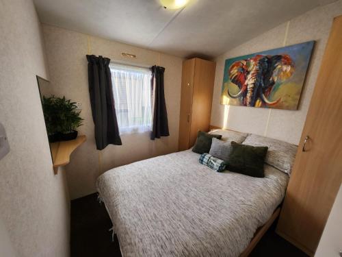 a small bedroom with a bed and a window at Comfy caravan on marine park in Rhyl