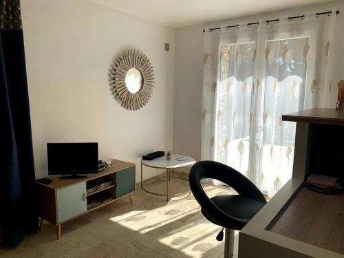 uma sala de estar com uma cadeira e uma televisão em Chez ALYS - Appartement Sarlat em Sarlat-la-Canéda