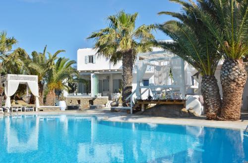 a swimming pool with palm trees and a house at Zephyros in Paraga