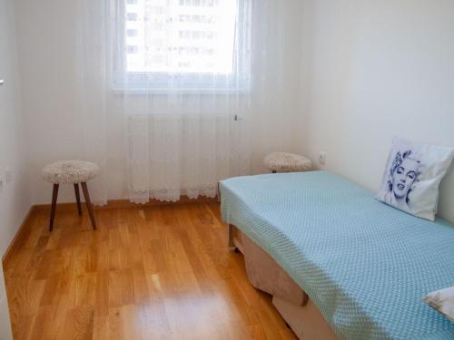 1 dormitorio con cama, ventana y suelo de madera en Apartman Valerija, en Doboj