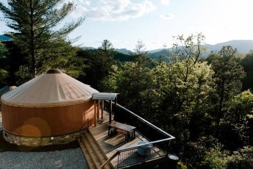 a yurt with a bench on a deck with trees at Santeetlah @ Sky Ridge Yurts in Bryson City