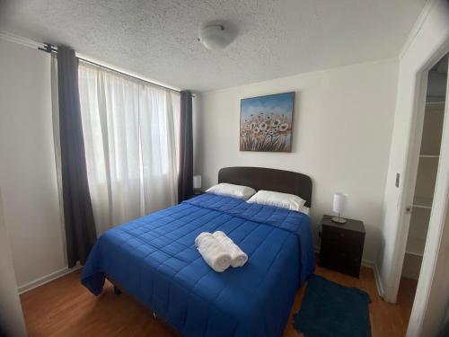 a bedroom with a blue bed with towels on it at Apartamento altos del boldo in Curicó