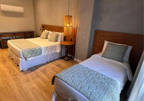 a hotel room with two beds and a table at Kastel Petrópolis in Petrópolis