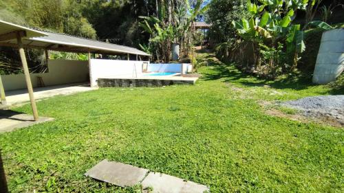 a yard with a grassy yard with a pool at ESPAÇO ShEHERAZADE PISCINA & LAZER in Juquitiba