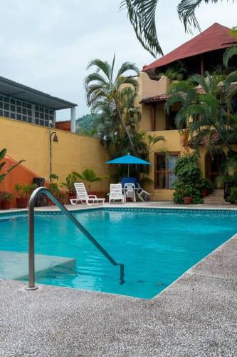 a swimming pool in front of a building at Casabu in Zihuatanejo