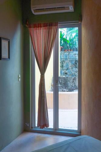 a bedroom with a window with a curtain in front at Casabu in Zihuatanejo