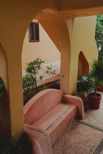 a patio with a couch and an arch with plants at Casabu in Zihuatanejo