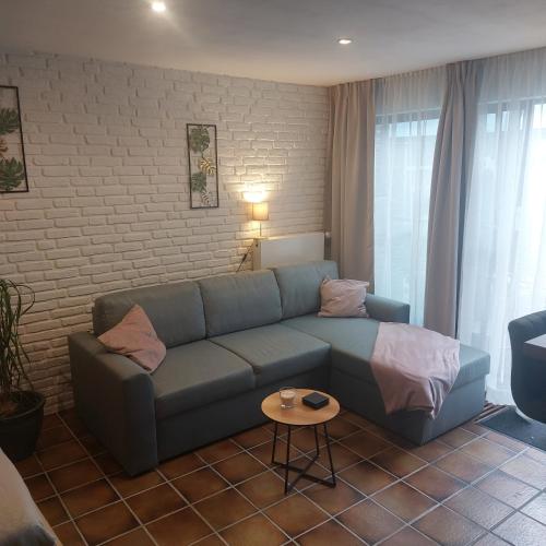 a living room with a blue couch and a table at Os Heem in Wittem