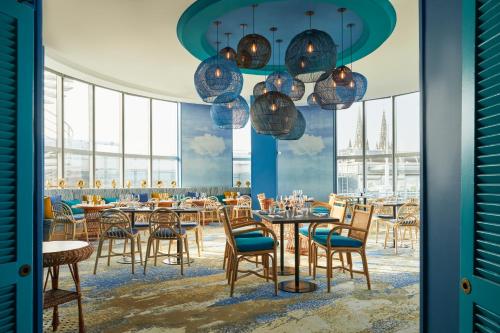 a dining room with tables and chairs and windows at Hotel Indigo Bordeaux Centre Chartrons, an IHG Hotel in Bordeaux