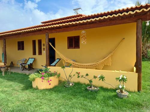 a yellow house with a hammock in the yard at Recanto falésias do gostoso in São Miguel do Gostoso