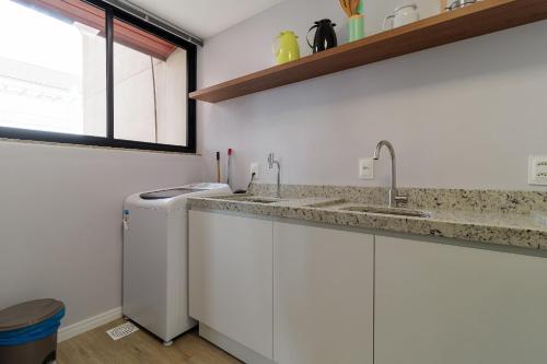 eine Küche mit weißen Schränken, einem Waschbecken und einem Fenster in der Unterkunft Sossego frente mar com vista para a ilha CCA201 in Florianópolis