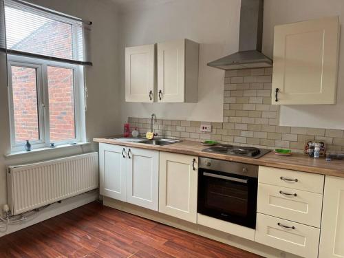 a kitchen with white cabinets and a stove top oven at The First-central Wigan 8 guests in Wigan