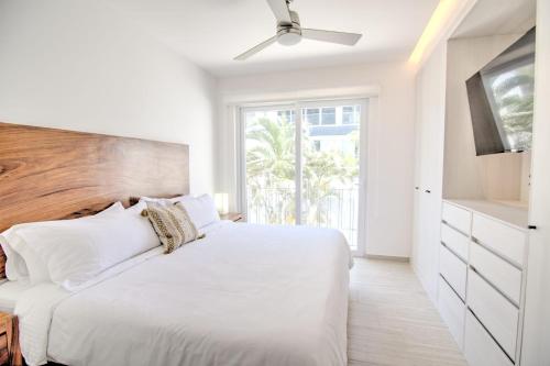 une chambre blanche avec un grand lit et une fenêtre dans l'établissement Casa Las Palmas - Condos by the Beach with Rooftop Pool, à Bucerías