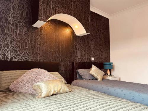 a bedroom with two beds and a light above them at The First-central Wigan 8 guests in Wigan