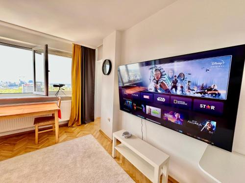 ein Wohnzimmer mit einem großen Flachbild-TV an der Wand in der Unterkunft ORANGE 3 fast WiFi 1Gbs 85'TV Netflix HBO Disney+ SkyShowMax in Warschau