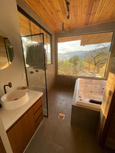 a bathroom with a tub and a sink with a window at Vila Libélula, Cavalcante in Cavalcante