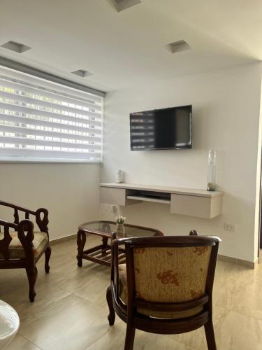 a living room with a tv and a table and chairs at Suite Los Sauces in Ibarra
