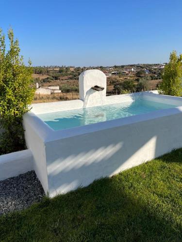 a swimming pool with a bench in the grass at Casa das Chaminés in Santo António do Baldio