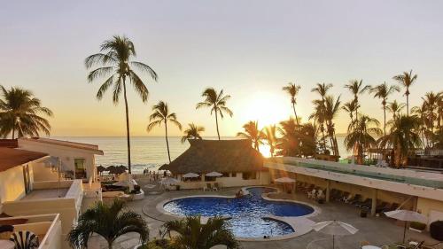 a resort with a pool and palm trees and the ocean at Costa Dorada - Beachfront Penthouse in Bucerias Golden Zone in Bucerías