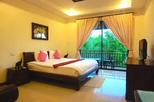 a bedroom with a bed and a balcony with a window at Thai Pura Resort in North Pattaya