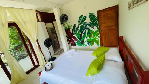 a bedroom with a bed with green pillows and a window at Hotel talú tayrona in El Zaino