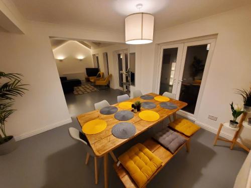 a dining room with a wooden table and yellow chairs at 5 bedroom, recently renovated house close to Hastings Beach in Hastings