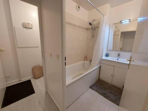 La salle de bains blanche est pourvue d'une baignoire, d'un lavabo et d'une douche. dans l'établissement Appartement Propre et Paisible Confort et Sérénité Assurés, à Moissy-Cramayel
