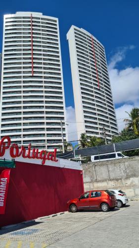 una macchina rossa parcheggiata di fronte a due edifici alti di Ponta Negra RN03 a Natal