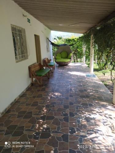 een patio met een bank en een stoel op een stenen vloer bij Altos del Reposo Casa Campestre in Pueblo Bello