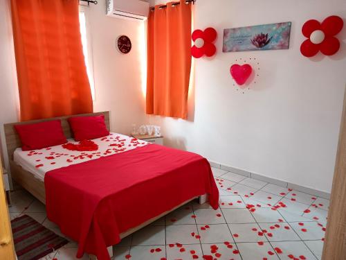 ein Schlafzimmer mit einem roten Bett mit Blumen auf dem Boden in der Unterkunft Maison d'une chambre avec piscine partagee terrasse amenagee et wifi a Petit Bourg in Petit-Bourg