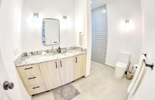 La salle de bains blanche est pourvue d'un lavabo et d'un miroir. dans l'établissement Estadios Suites - Only 3 Blocks to Beach, à Bucerías