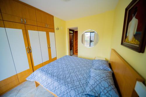 a bedroom with a blue bed and a mirror at Edificio Martha Schwantz in Guarapari