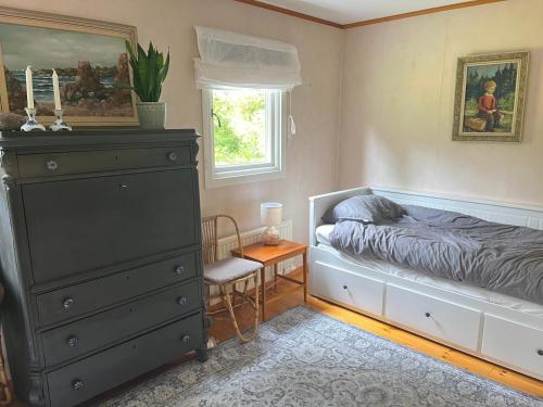 a bedroom with a bed and a dresser and a window at Stuga Sövde in Sövde