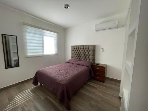 a bedroom with a bed with a purple bedspread and a window at Depto. totalmente nuevo y amueblado in Mazatlán
