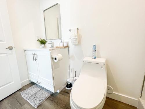 Baño blanco con aseo y espejo en Cozy Habitat, en Los Ángeles