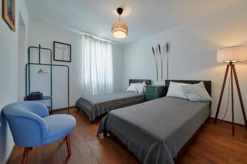 - une chambre avec deux lits et une chaise bleue dans l'établissement Valesi holiday home, à Rakalj
