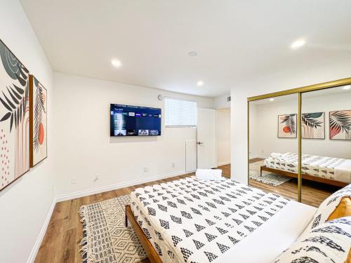 Comfy 2-bedroom home in Hollywood في لوس أنجلوس: غرفة نوم مع سرير وتلفزيون على الحائط