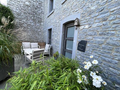 a patio with two chairs and flowers in front of a building at L’Aragne in Dinant