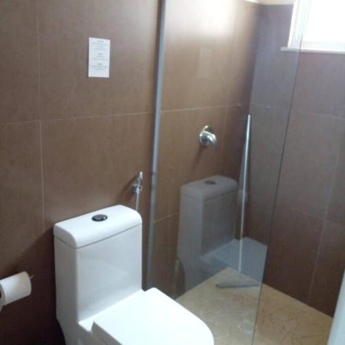 a bathroom with a toilet and a glass shower at Vista do paraíso AP 09 Condomínio vilas na Praia Residente in Canoa Quebrada